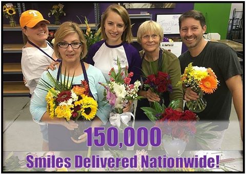 People holding flowers with text that says 150,000 Smiles Delivered Nationwide