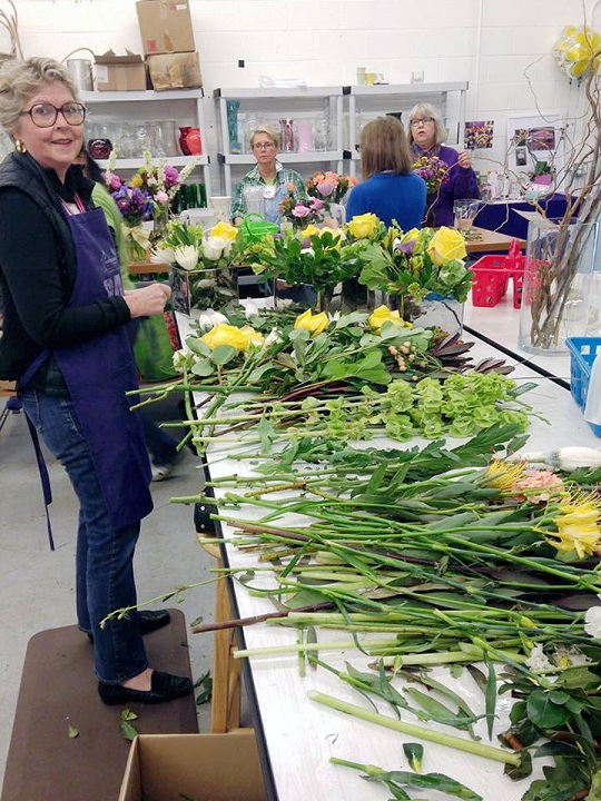 Volunteer standing on GelPro mat while working at a table of flowers